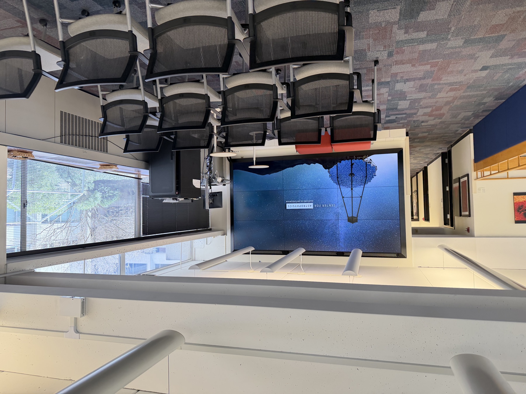 An SAO conference room with rows of chairs facing a large video wall showing the Center for Astrophysics logo.