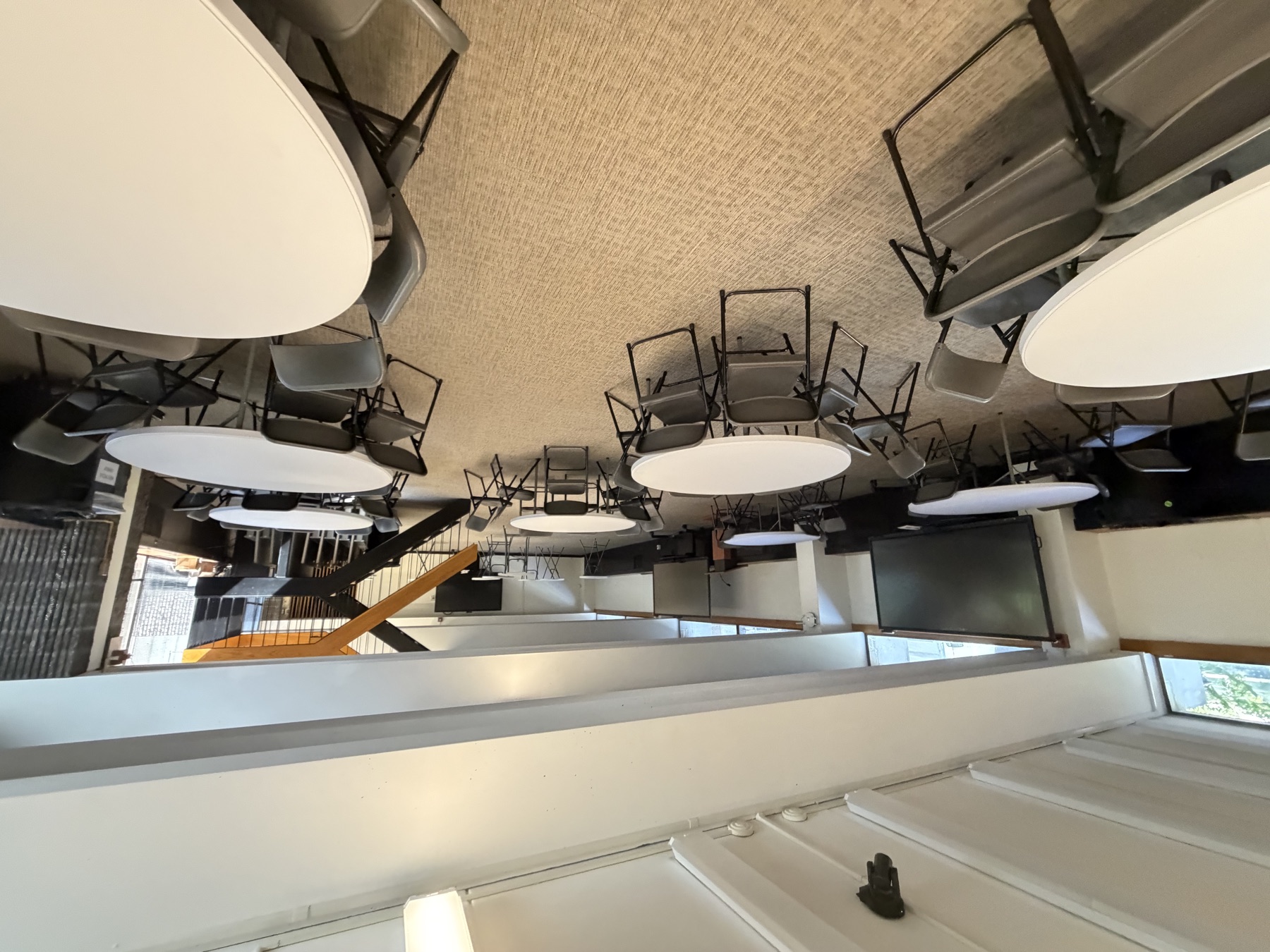 A flexible meeting room at SAO with round tables and chairs beside tall windows.